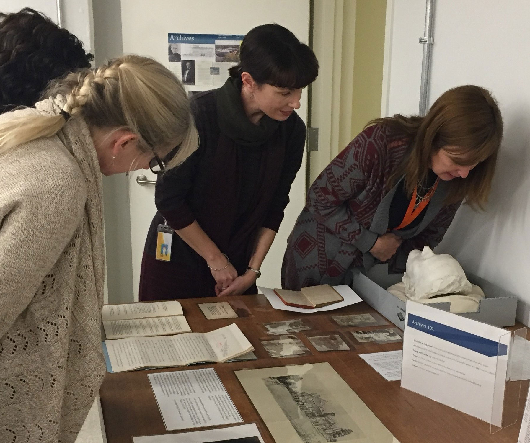 4 women looking at physical documents from the Archives